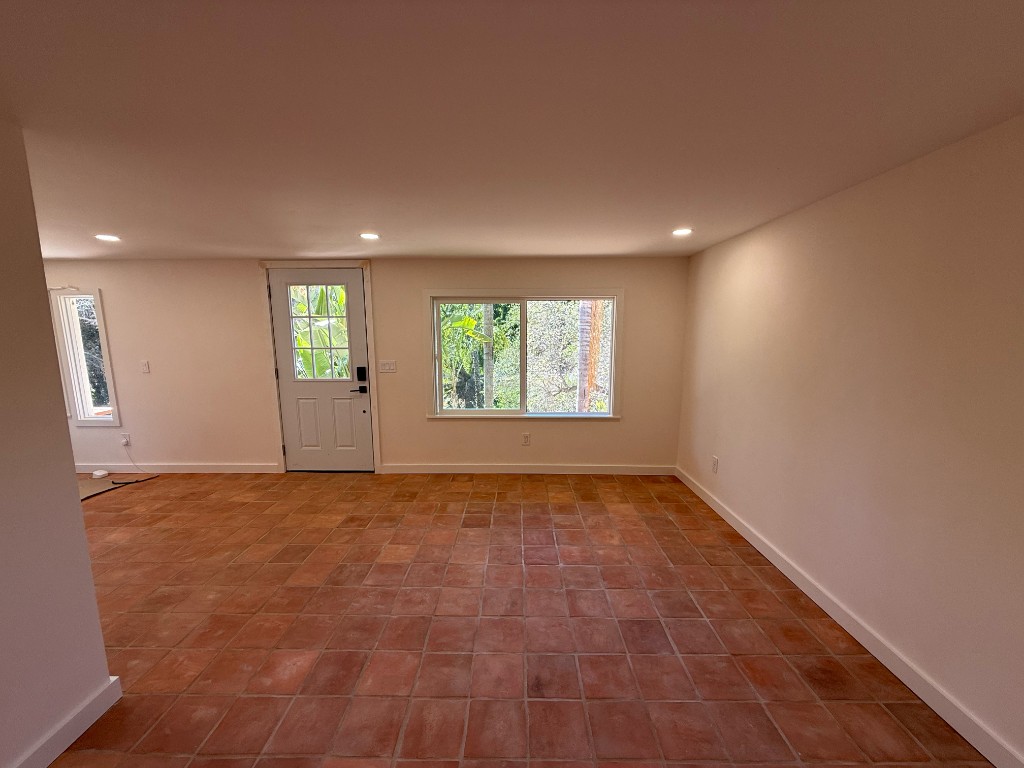 Finished casita living room with terracotta tile, can lights, and a garden door