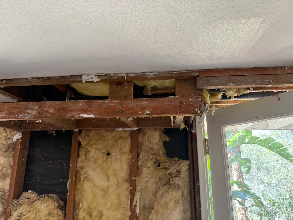 Old filthy insulation and open framing above a door header