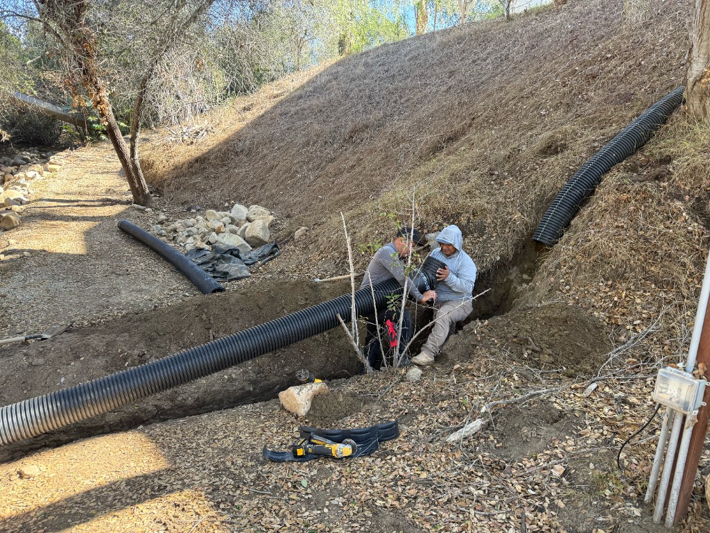 CRG crew joining corrugated drain in a hillside trench